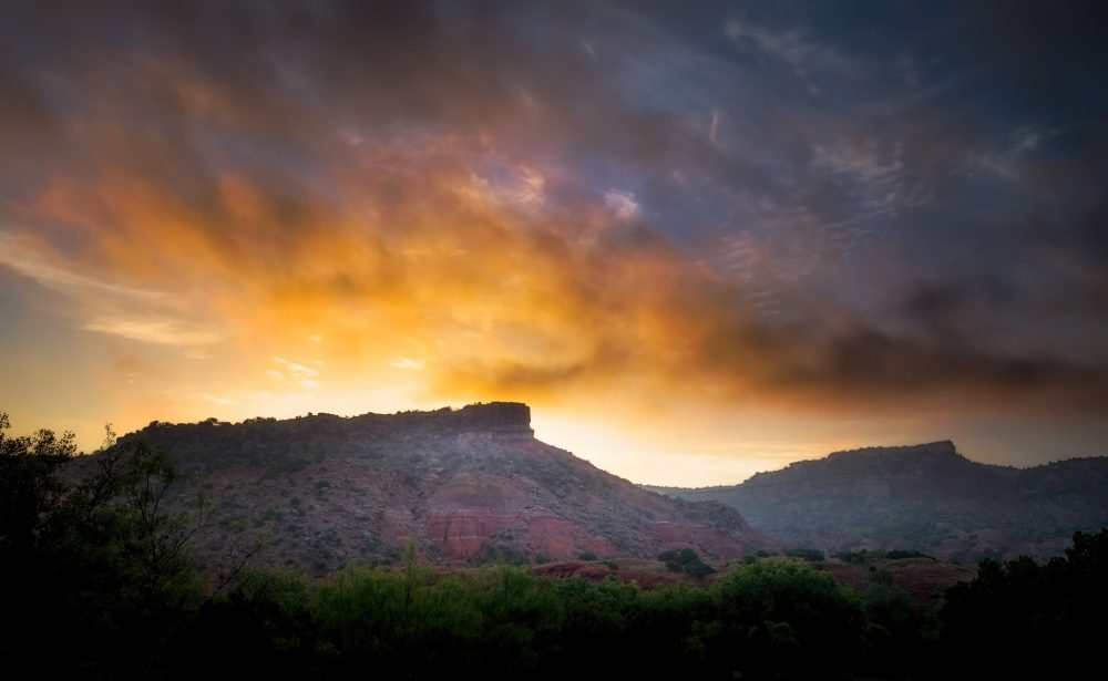 Sunrise glowing behind rock mountains at Palo Duran Canyon State Park in Texas